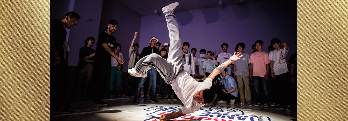 Image of a person break dancing in front of a gathered crowd