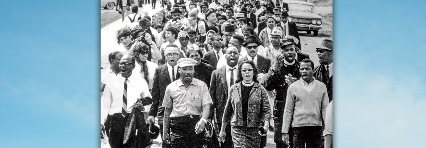 Black & white photo of MLK Jr. marching in protest with a group of people