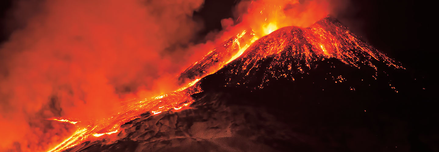Volcano erupting with glowing orange lava flowing down its slopes and red smoke billowing from the crater